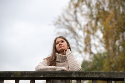 Portrait of woman against snow covered railing during winter