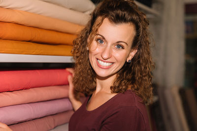 Radiant young woman with curly hair selecting fabrics in a colorful store