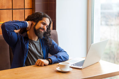 Young man using mobile phone while sitting on table