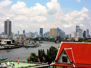 Buildings by river against sky in city