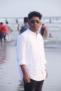 Portrait of young man standing at beach