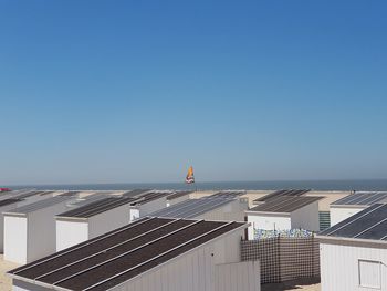 Buildings by sea against clear blue sky