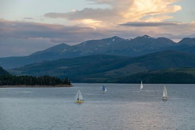 Sailboat in sea against mountains during sunset