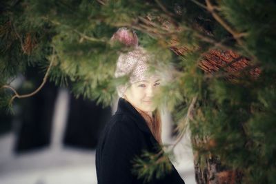Portrait of woman standing by tree during winter