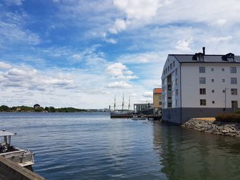 Scenic view of river by buildings against sky