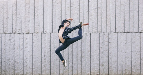 Full length of man jumping while dancing against wall