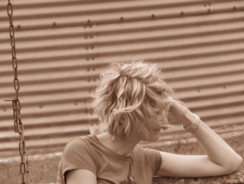 Woman sitting against corrugated iron