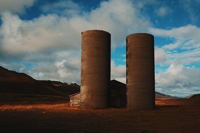 Smoke stack on field against sky