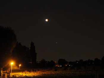 Illuminated street lights against clear sky at night