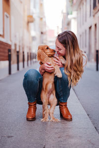 Smiling woman playing with dog in city