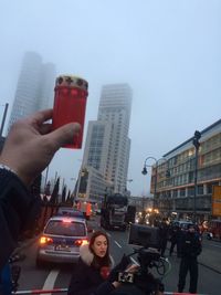 Midsection of woman photographing city against sky