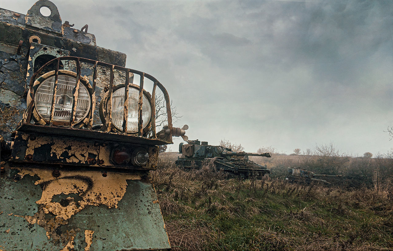 ABANDONED METAL STRUCTURE AMIDST FIELD AGAINST SKY