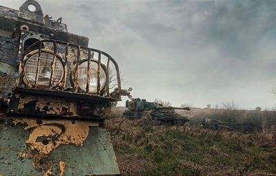 Abandoned metal structure on field against sky