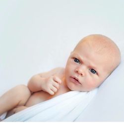 Portrait of cute baby girl sitting against white background