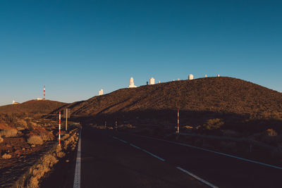 Empty road against clear blue sky