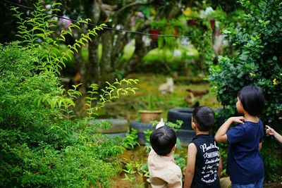 Rear view of kids standing amidst plants