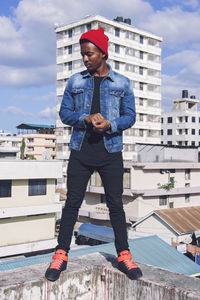 Young man standing on retaining wall against building