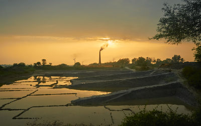 Scenic view of agricultural field against sky during sunset