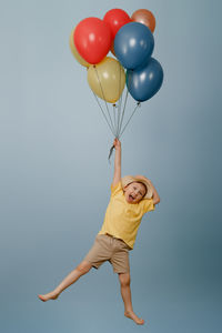 Low angle view of woman with balloons against blue background