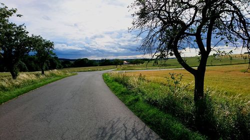 Road amidst field against sky