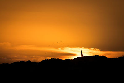 Silhouette man standing against orange sky