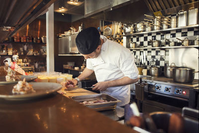 Chef chopping onion cutting board in kitchen at restaurant