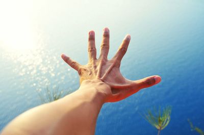 Cropped hand of man reaching over sea