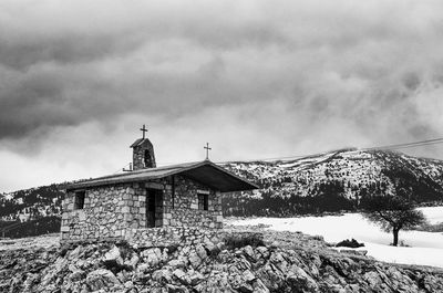 Built structure on snow covered mountain against sky