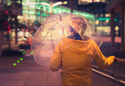 Man holding umbrella while standing on street during rainy season