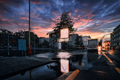 Reflection of trees in swimming pool against sky at sunset
