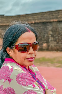 Woman wearing sunglasses against brick wall