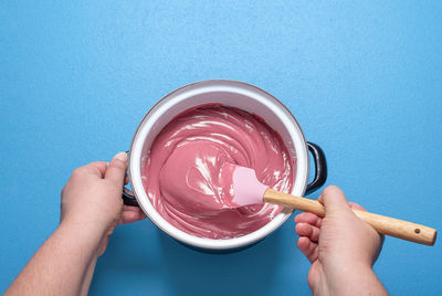 Midsection of woman holding ice cream against blue background