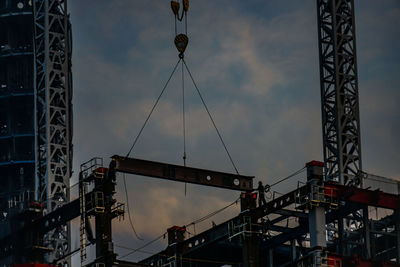 Low angle view of silhouette cranes against sky at dusk