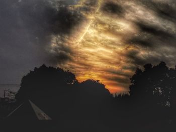 Silhouette trees against dramatic sky during sunset