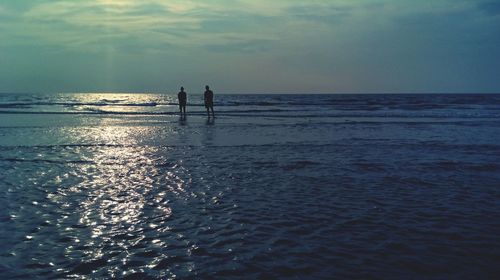 Silhouette men at beach against sky