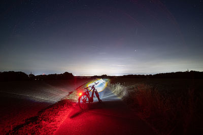 Rear view of man walking on beach against sky at night
