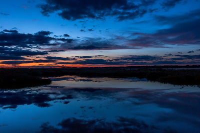 Scenic view of dramatic sky over lake during sunset