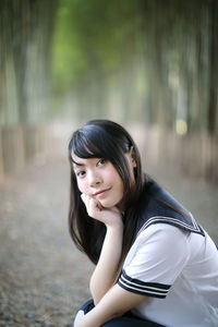 Portrait of beautiful young woman sitting against blurred background