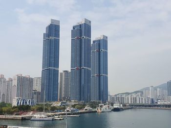 Modern buildings by river against sky in city