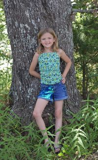 Portrait of a smiling young woman standing on tree trunk