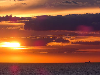 Scenic view of sea against dramatic sky during sunset