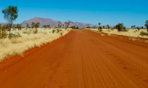 Tire tracks on desert road against clear sky