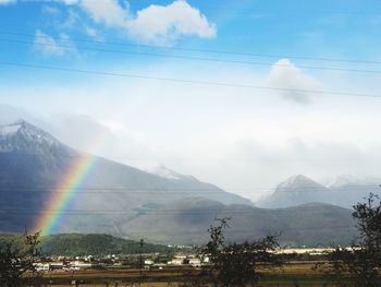 Scenic view of rainbow over mountains against sky