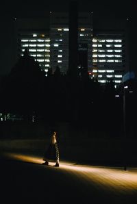 Woman walking on road in city at night