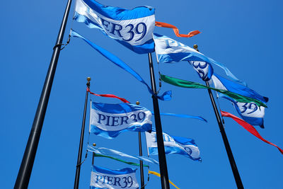 Low angle view of flags against blue sky