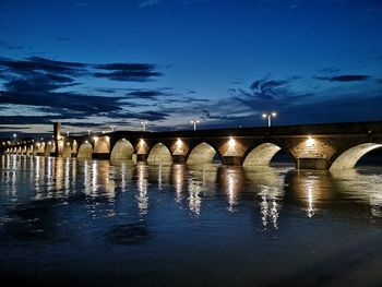 Arch bridge over river against sky at night