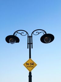 Low angle view of street lights against clear blue sky