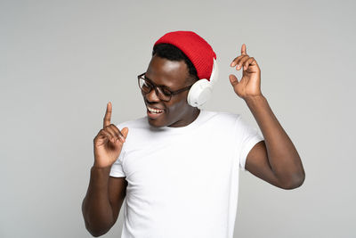 Young man dancing while listening music against white background