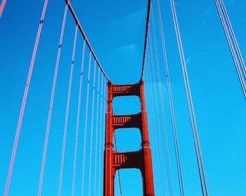 Low angle view of suspension bridge against clear blue sky