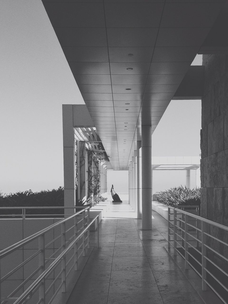 architecture, built structure, railing, indoors, building exterior, sunlight, the way forward, connection, bridge - man made structure, architectural column, clear sky, day, sky, column, empty, building, city, shadow, no people, bridge